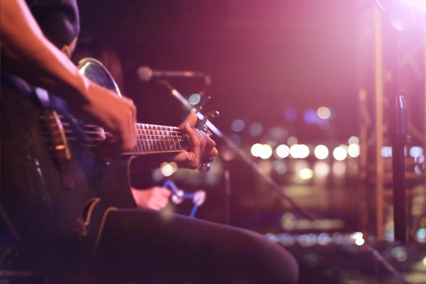 Nahaufnahme eines Musikers mit seiner Gitarre auf der Bühne.